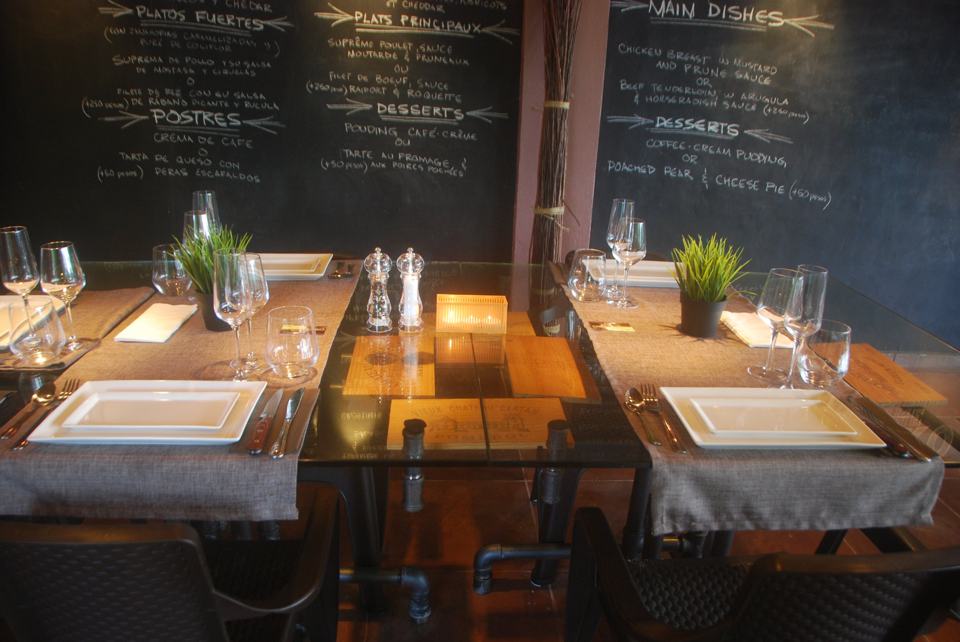 Une table dressée : chemin de table en lin, assiettes blanches, verres à vin